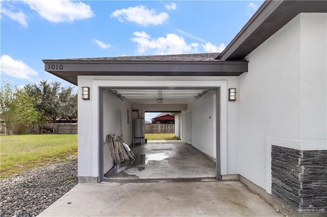 garage with water heater, driveway, and fence