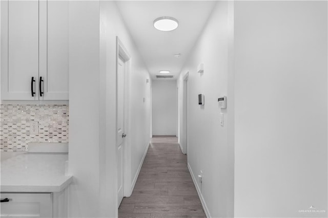 hall with light wood-type flooring, visible vents, and baseboards