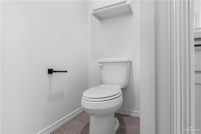 bathroom with wood finished floors, toilet, and baseboards