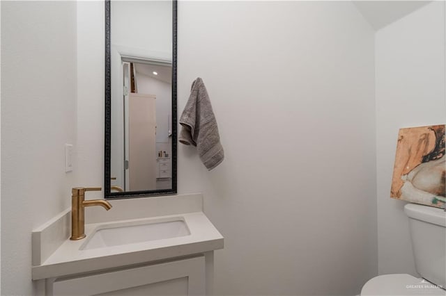 bathroom featuring vanity, toilet, and lofted ceiling