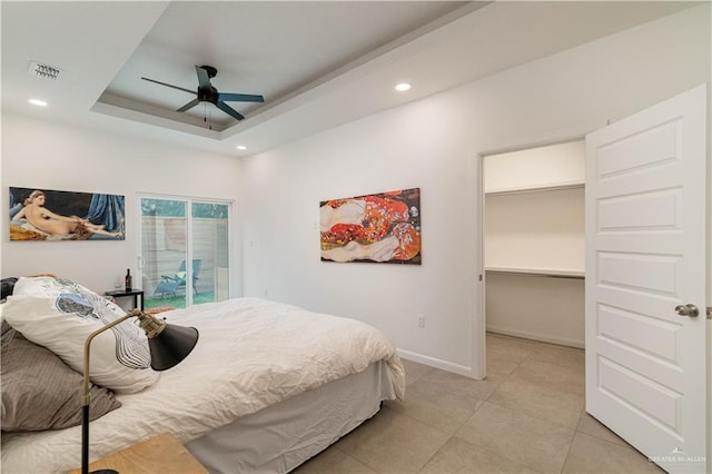 bedroom featuring a tray ceiling, access to exterior, ceiling fan, and light tile patterned floors