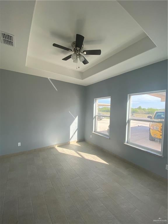 spare room with wood-type flooring, a tray ceiling, and ceiling fan