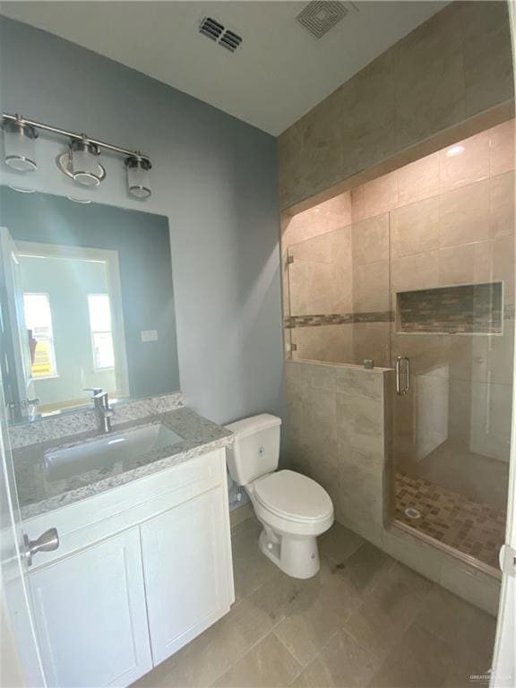 bathroom with vanity, toilet, a shower with door, and tile walls