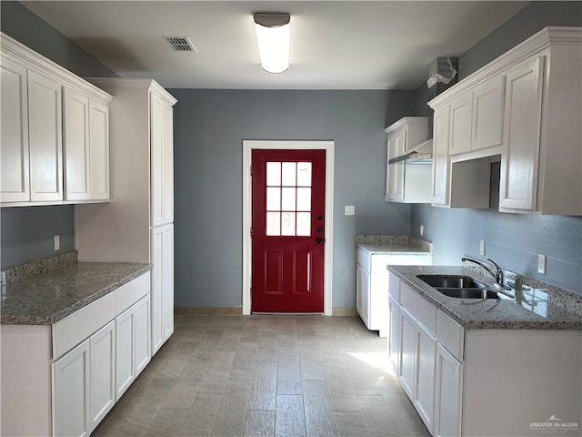 kitchen with white cabinetry, sink, and light wood-type flooring