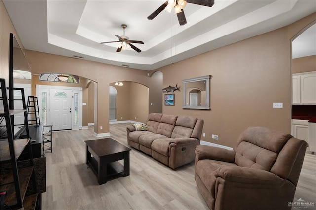 1614 Gabriels Lndg, Harlingen, TX 78550 - living area featuring arched walkways, a tray ceiling, ceiling fan, baseboards, and light wood-style flooring
