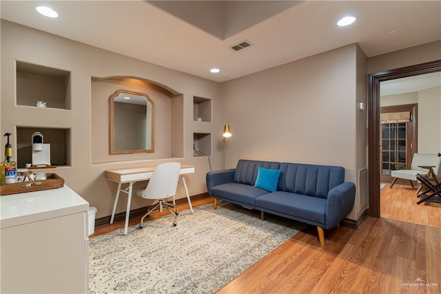 living room with recessed lighting, visible vents, and wood finished floors