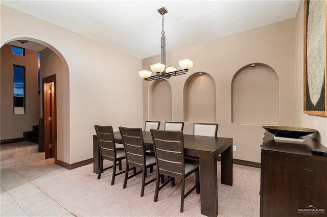 dining space featuring an inviting chandelier, baseboards, light tile patterned floors, and arched walkways