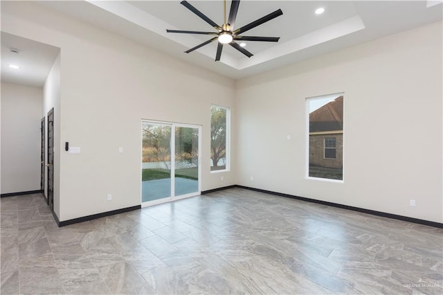 unfurnished room with ceiling fan, a tray ceiling, and a towering ceiling