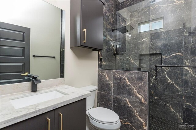 bathroom with a tile shower, vanity, and toilet