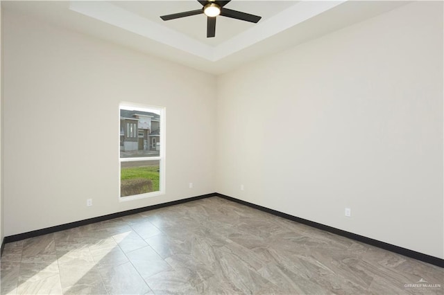 spare room featuring a tray ceiling and ceiling fan