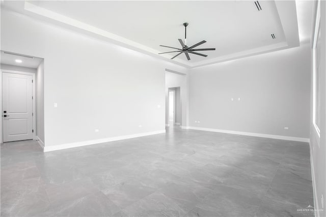 empty room with a raised ceiling and ceiling fan