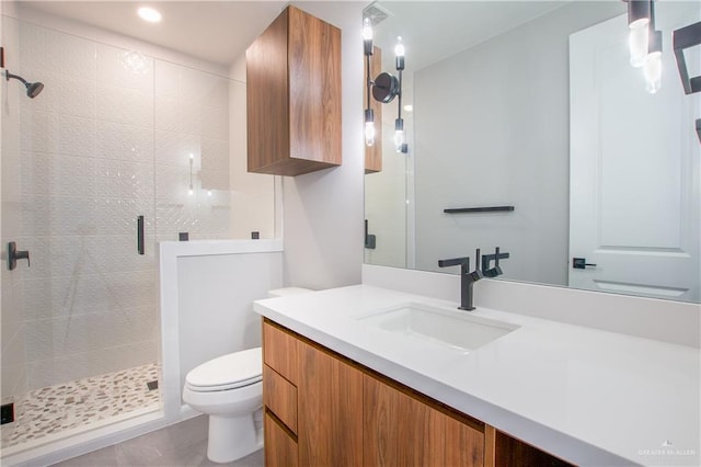 bathroom featuring a shower with door, vanity, and toilet