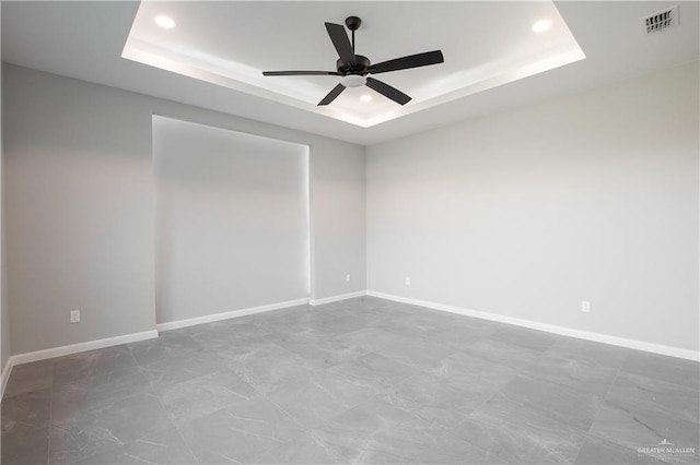 unfurnished room featuring a raised ceiling and ceiling fan