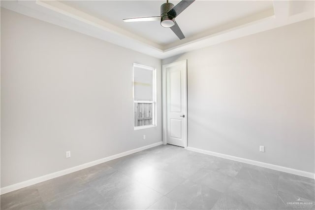 spare room featuring ceiling fan and a raised ceiling