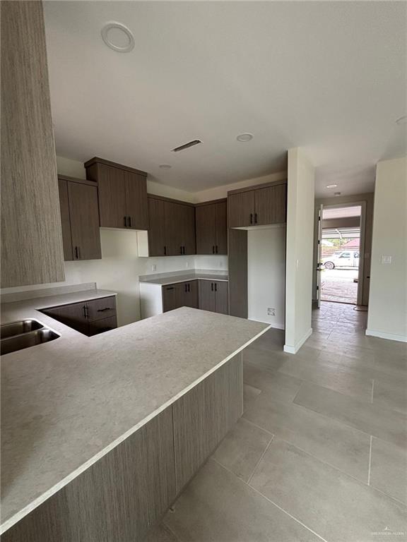 2213 Dorado Dr, Mission, TX 78573 - kitchen with dark brown cabinetry, light countertops, and a peninsula
