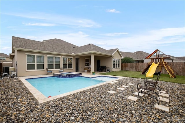 view of swimming pool featuring a playground, a patio area, an in ground hot tub, and a lawn