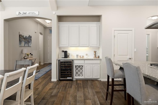 bar featuring wine cooler, white cabinets, tasteful backsplash, and light stone countertops