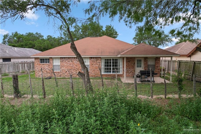 rear view of house with a lawn, a patio area, brick siding, and a fenced backyard