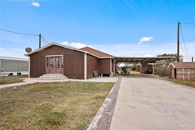 view of front of house with a front lawn, an outdoor structure, and a carport