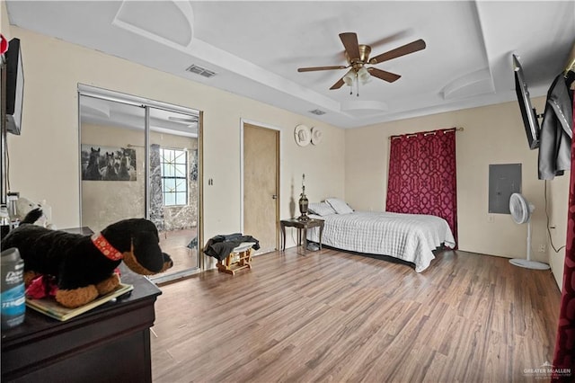 bedroom with a tray ceiling, ceiling fan, a closet, and hardwood / wood-style flooring