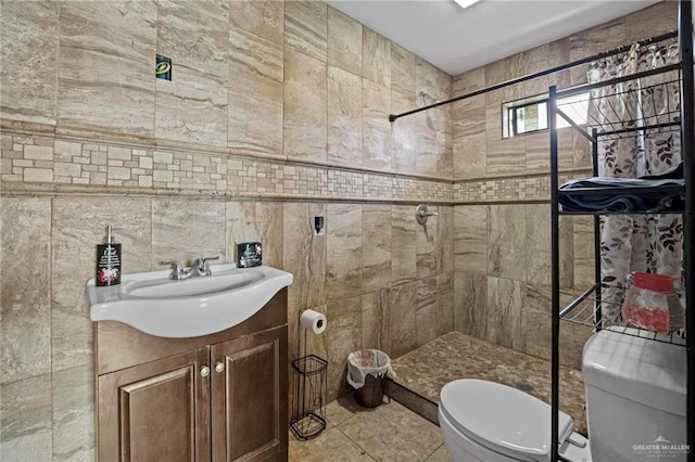 bathroom with vanity, a shower, tile patterned floors, toilet, and tile walls