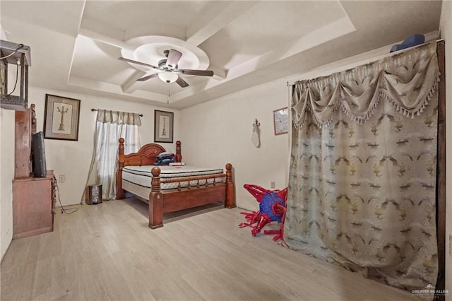 bedroom with a raised ceiling, ceiling fan, and light hardwood / wood-style flooring