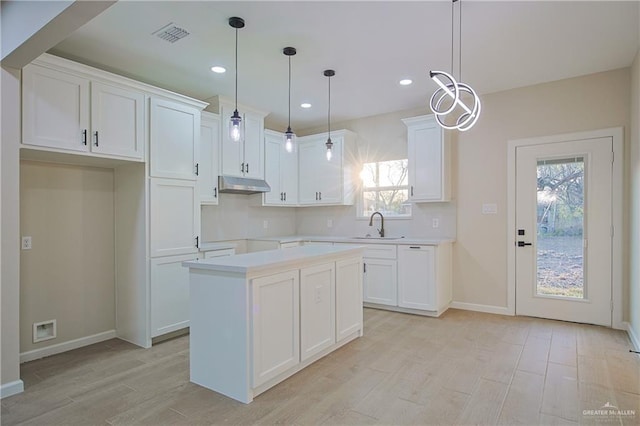 kitchen with sink, plenty of natural light, a kitchen island, pendant lighting, and white cabinets