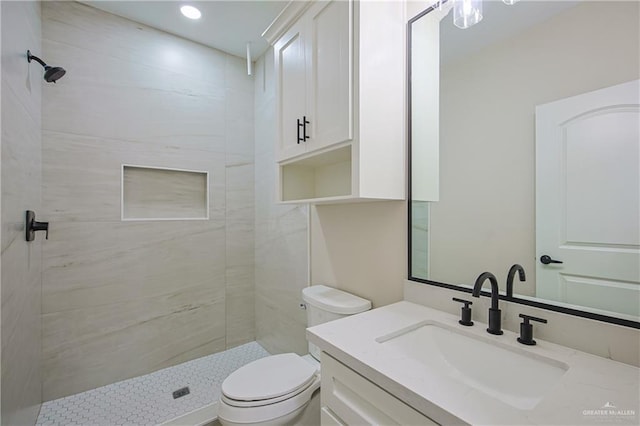 bathroom featuring vanity, a tile shower, and toilet