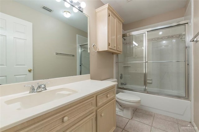 full bathroom featuring shower / bath combination with glass door, tile patterned flooring, vanity, and toilet