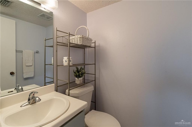 bathroom with vanity, toilet, and a textured ceiling