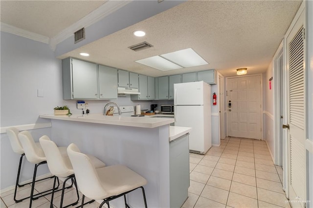 kitchen featuring a kitchen bar, kitchen peninsula, crown molding, and white refrigerator