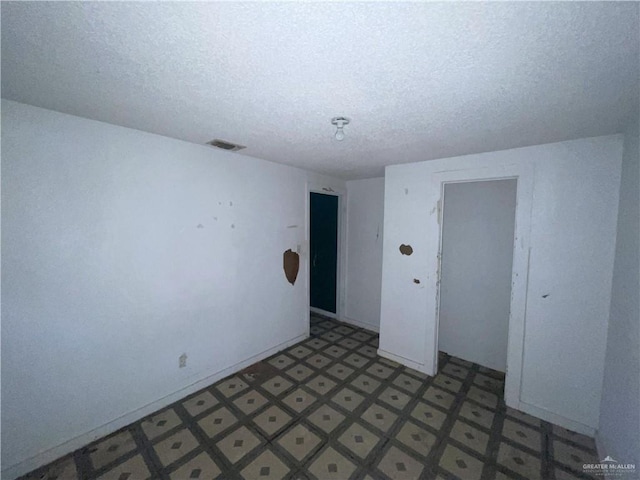 empty room with tile patterned floors, visible vents, and a textured ceiling