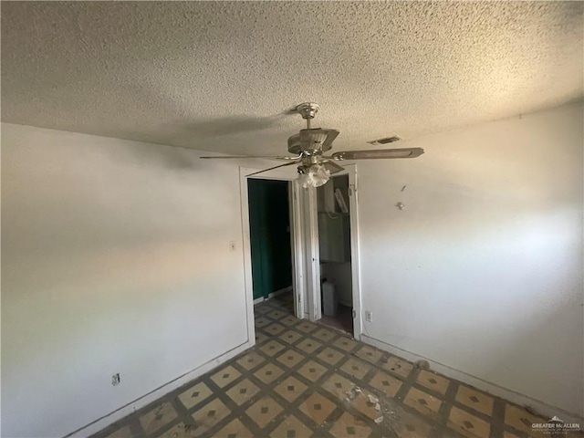 empty room featuring ceiling fan, tile patterned floors, and a textured ceiling