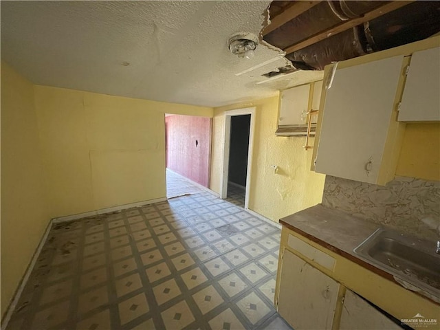 kitchen featuring a sink, tasteful backsplash, light floors, and a textured ceiling