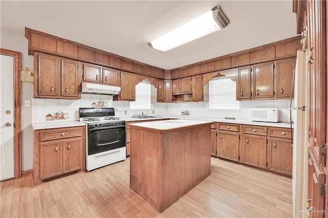 kitchen with a center island, white appliances, a wealth of natural light, and light hardwood / wood-style flooring