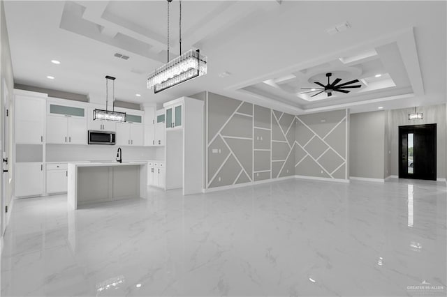 unfurnished living room with ceiling fan, a raised ceiling, and sink