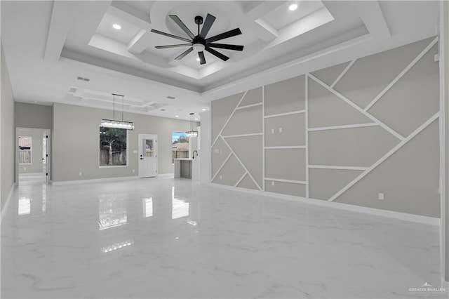 unfurnished living room featuring a raised ceiling and ceiling fan