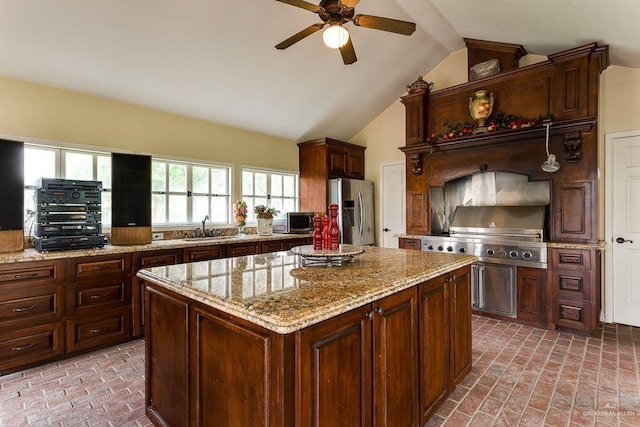 kitchen with light stone counters, sink, stainless steel appliances, and vaulted ceiling