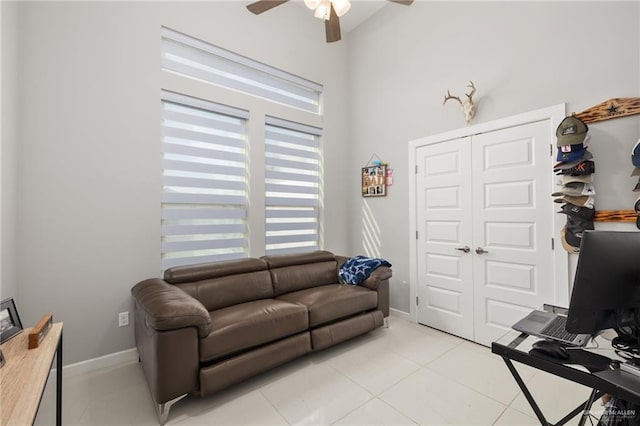 living room with ceiling fan, light tile patterned flooring, and baseboards