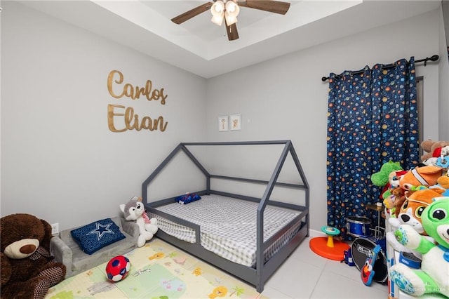 bedroom with tile patterned flooring, a raised ceiling, and ceiling fan