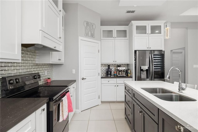 kitchen with electric range, white cabinetry, stainless steel refrigerator with ice dispenser, a sink, and light tile patterned flooring