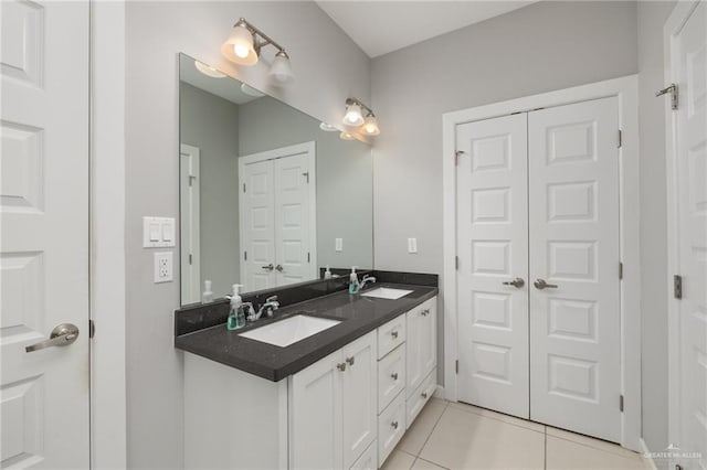 full bath featuring a closet, double vanity, a sink, and tile patterned floors