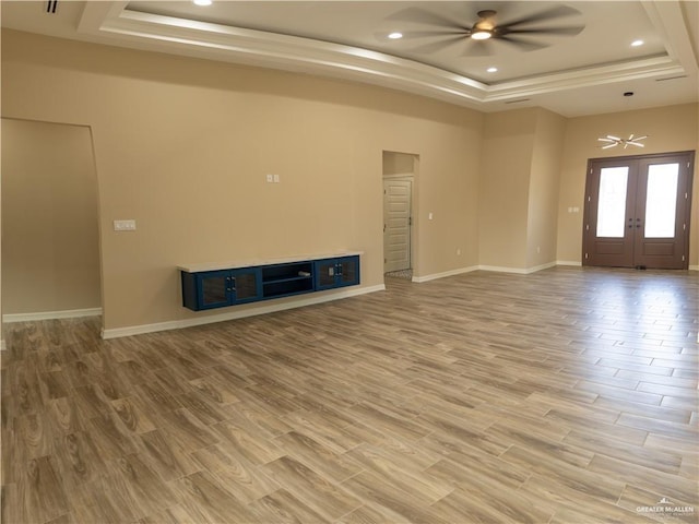 unfurnished living room with ceiling fan, a raised ceiling, wood-type flooring, and french doors