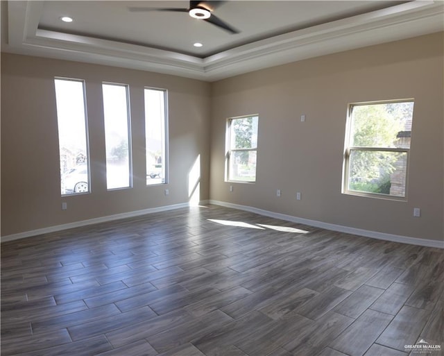 spare room with a tray ceiling, ceiling fan, a healthy amount of sunlight, and dark hardwood / wood-style floors