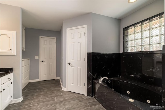 1608 Merlin Dr, Mission, TX 78572 - bathroom featuring a jetted tub, baseboards, wood finished floors, and vanity
