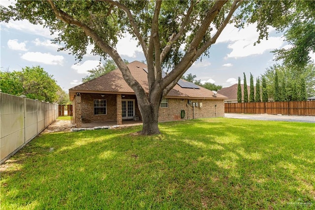 1608 Merlin Dr, Mission, TX 78572 - back of property with french doors, roof mounted solar panels, a patio area, brick siding, and roof with shingles