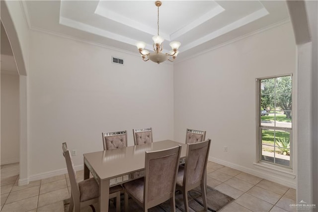 tiled dining area featuring a raised ceiling, ornamental molding, a healthy amount of sunlight, and a notable chandelier