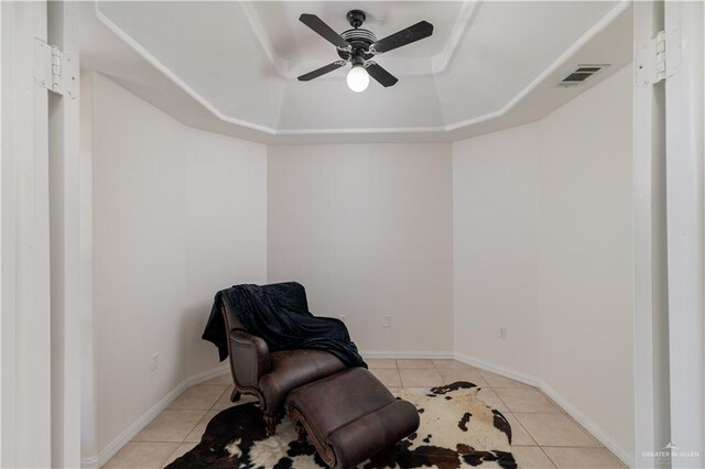 sitting room with light tile patterned floors, a tray ceiling, and ceiling fan