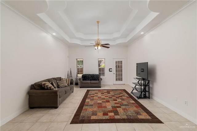 tiled living room featuring a raised ceiling, ceiling fan, and ornamental molding