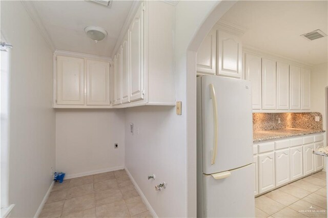 laundry area featuring light tile patterned floors and crown molding